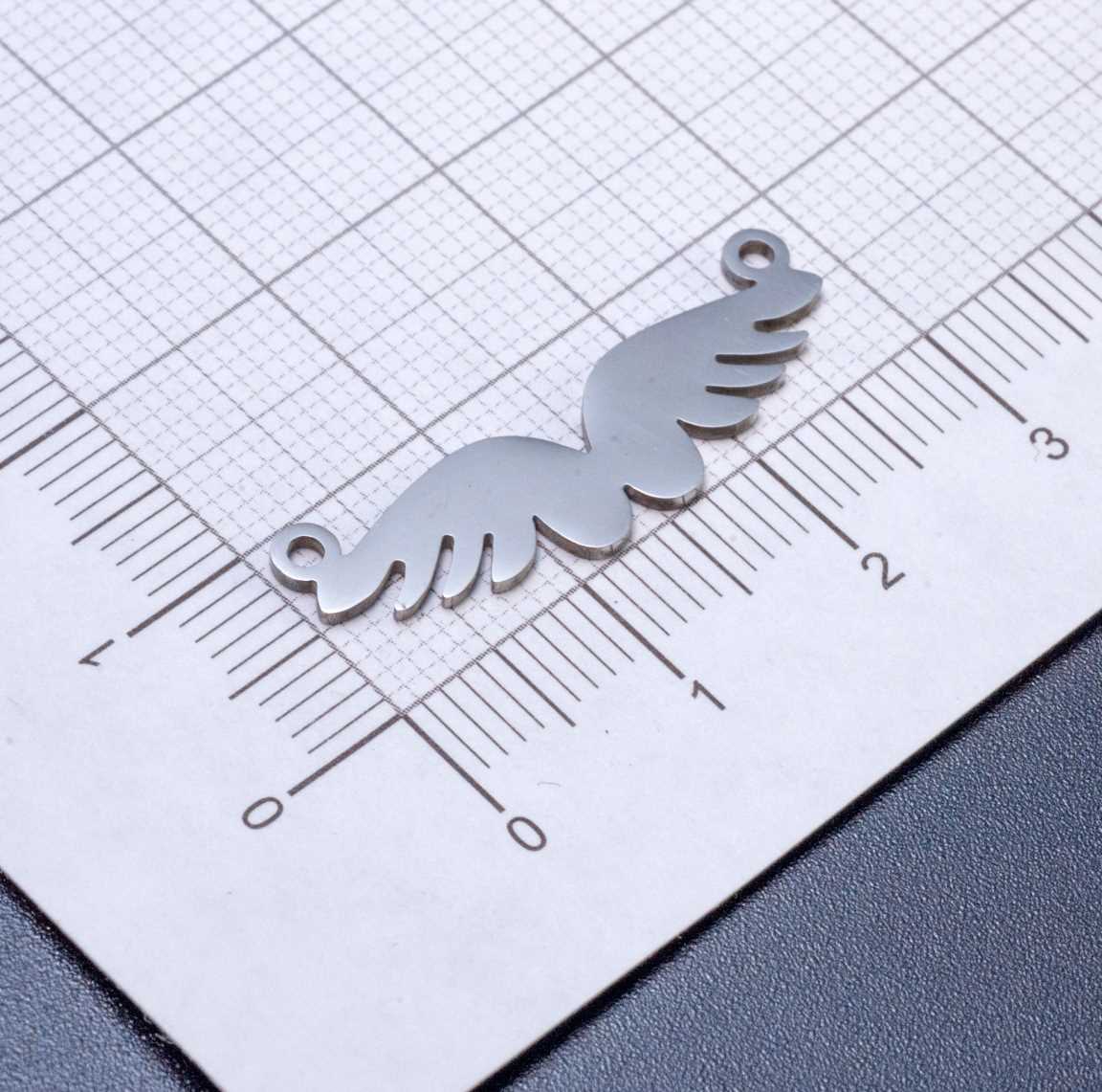 Подвеска-коннектор "Расправленные крылья" из полированной хирургической стали, размеры 28x9x1 мм, отверстие 1 мм, символизирует чистоту и свободу.