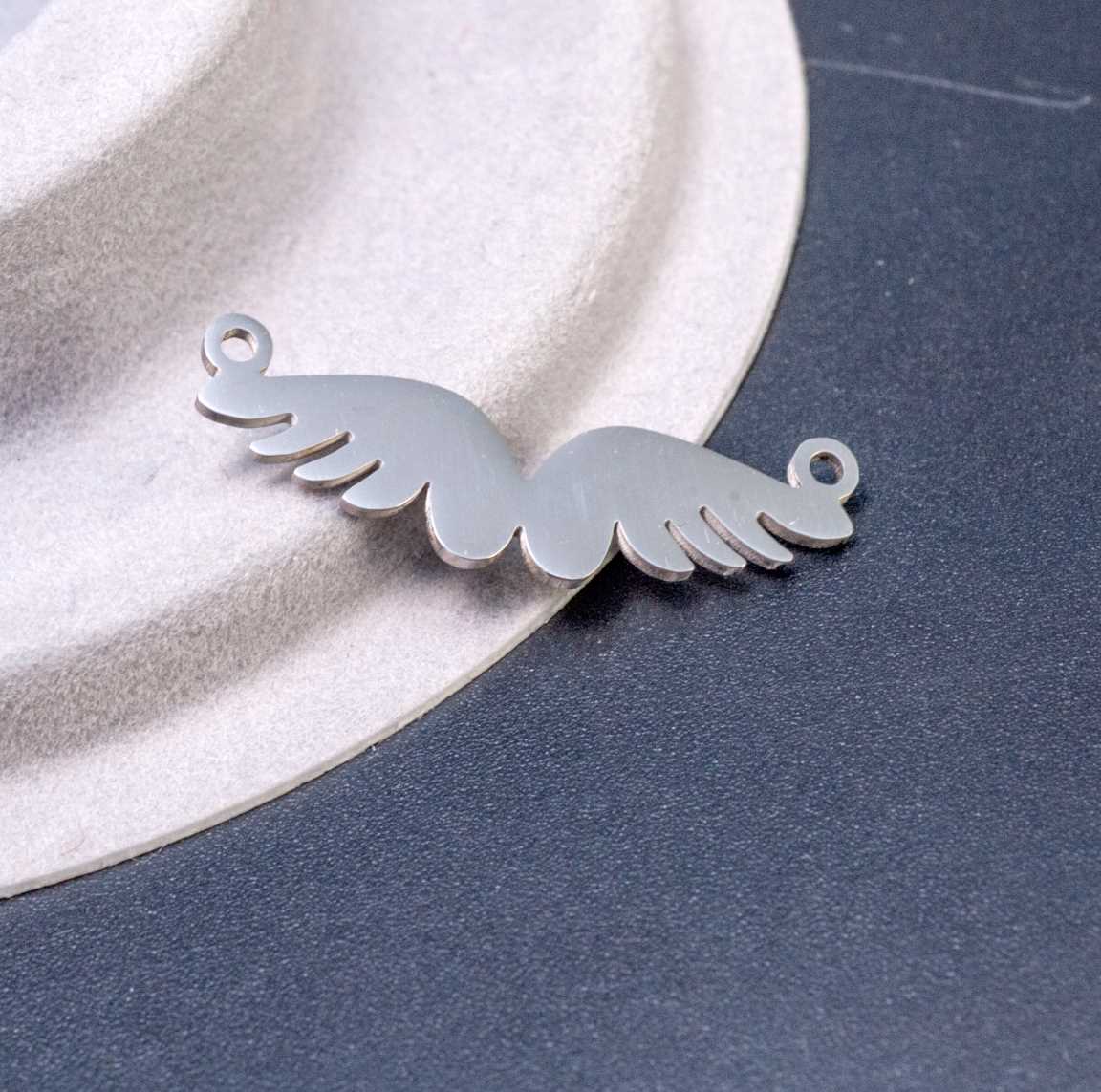 Подвеска-коннектор "Расправленные крылья" из полированной хирургической стали, размеры 28x9x1 мм, отверстие 1 мм, символизирует чистоту и свободу.